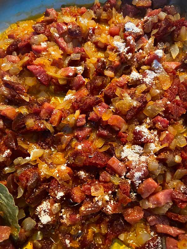 Pochando cebolla con jamón, chorizo y harina para cocinar llámpares a la sidra
