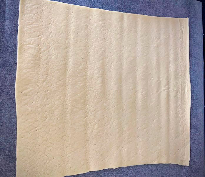 Primera masa de empanada sobre papel de horno para la empanada de bocartes