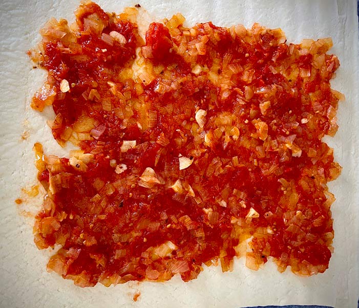 Primera capa de pisto sobre la masa para la empanada de bocartes