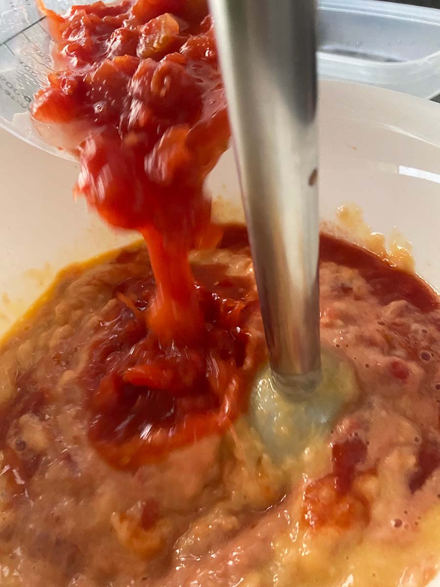Echando el tomate triturado al salmón y los huevos para el pastel de cabracho