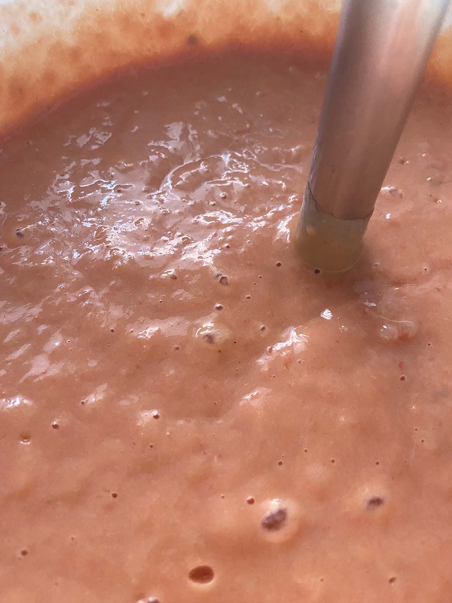 Echando el tomate triturado al salmón y los huevos para el pastel de cabracho