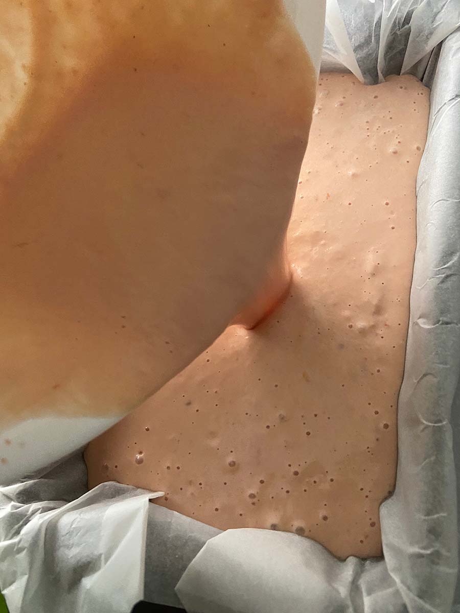 Llenando el molde forrado con papel de horno con la mezcla para pastel de cabracho