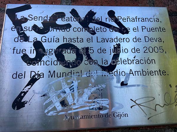 Placa conmemorativa de la inauguración de la senda peatonal del río Peñafrancia, que ha sido pintarrajeada.