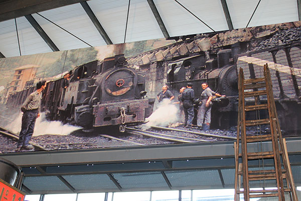 Mural que representa obreros ferroviarios al paso de una locomotora de vapor