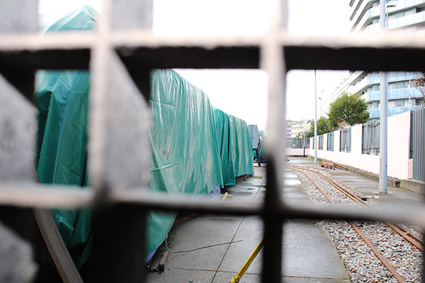 Elementos ferroviarios para rehabilitación estacionados y cubiertos con lonas en la zona de reserva no accesible al público en el museo del ferrocarril en Gijón