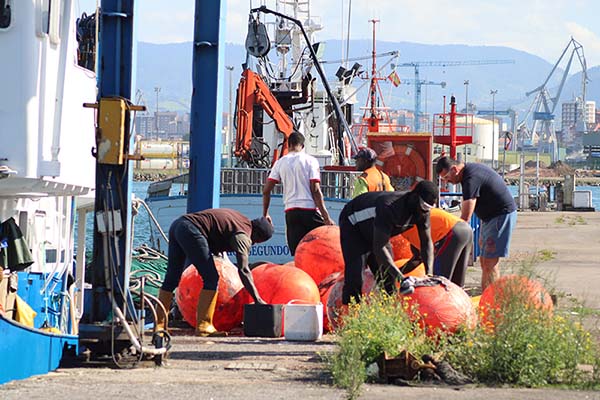 Miembros de la tripulación de un barco de pesca amarrado en el puerto del Musel en Gijón