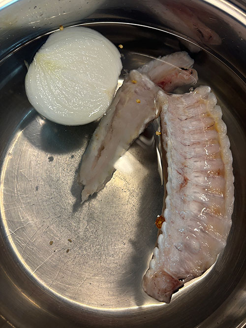Espinas de merluza, cebolla, guindilla y sal, para hacer el caldo de pescado