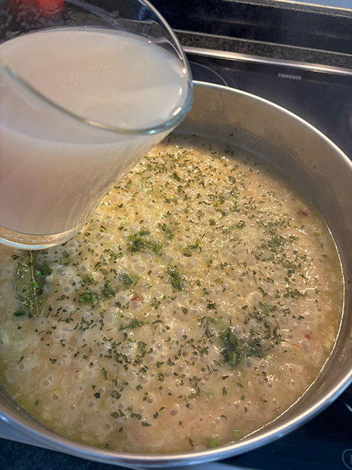 Añadiendo el caldo de pescado al pochado para la salsa verde