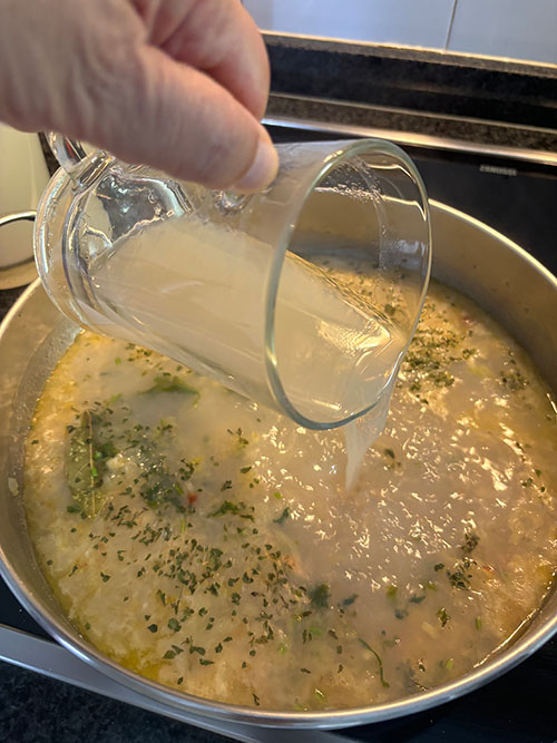 Añadiendo el caldo de cocción de los mejillones al pochado para la salsa verde
