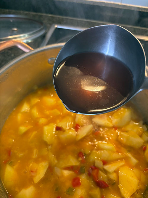 Añadiendo el caldo al guiso de pulpo de pedrero con patatinas