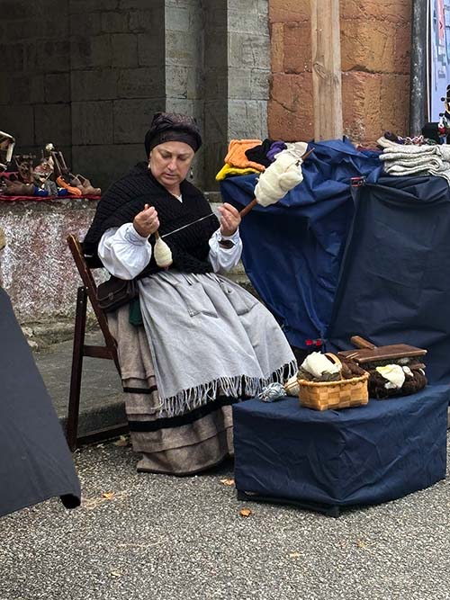 Mujer vaqueira hilando lana para tejer