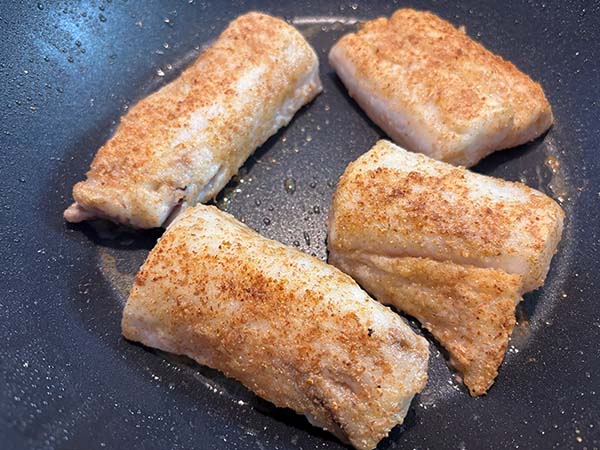 Sellando la merluza para prepararla a la sidra al estilo asturiano
