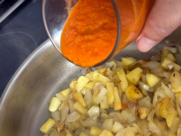 Pochando cebolla, ajo y manzana para la merluza a la sidra al estilo asturiano, añadiendo el tomate triturado