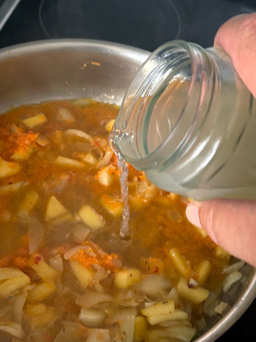 Pochando cebolla, ajo y manzana para la merluza a la sidra al estilo asturiano, añadiendo el caldo de pescado y mejillones