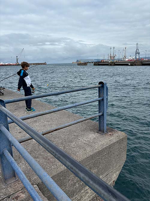 Niño pescando en el puerto del Musel en Gijón